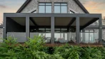 Terrasse et pergola avec garde-corps en verre à l’arrière d’une maison en pierre