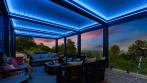 Terrasse avec pergola éclairée en DEL RVB bleu, coin salon et vue sur le coucher du soleil