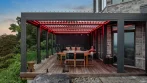 Terrasse avec pergola éclairée en rouge par des DEL RVB au-dessus d’une table à manger extérieure