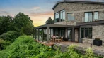 Pergola en aluminium Gris Ombre sur la terrasse d’une maison en pierre surélevée au coucher du soleil