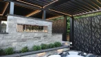 Backyard Pergola - photo 4 Stone fireplace pergola seen from the hot tub, with black louvers, LED lights and leaf-pattern privacy screens