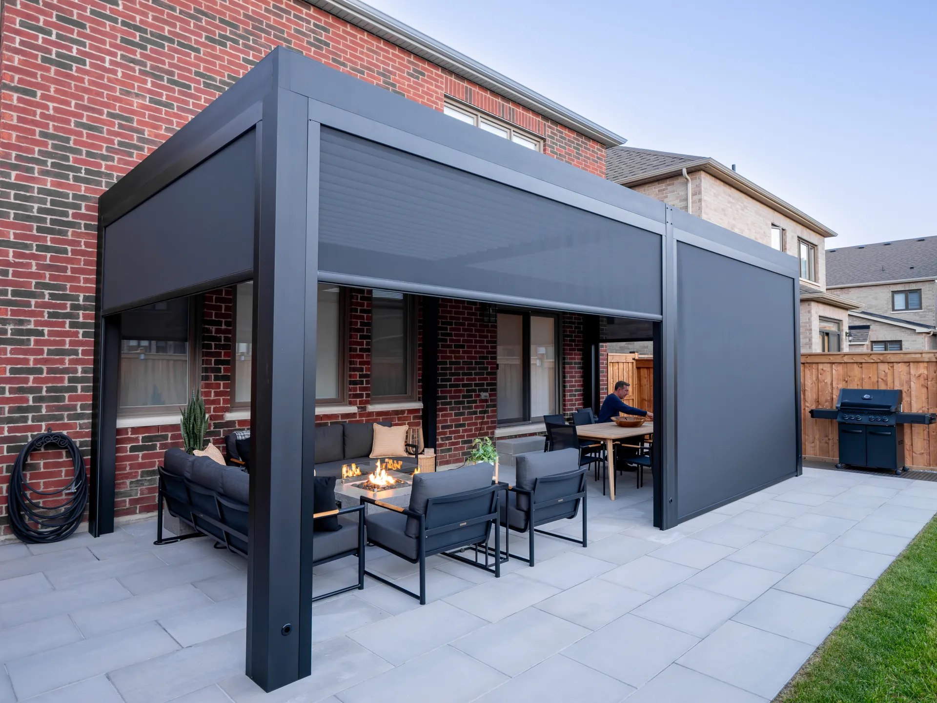 Attached aluminum pergola with three ZIP screens set at different heights around a fire table lounge and dining area