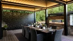 Backyard Pergola - photo 3 Pergola dining area with a table set for dinner, warm LED lights, laser-cut privacy panels and a linear gas fireplace