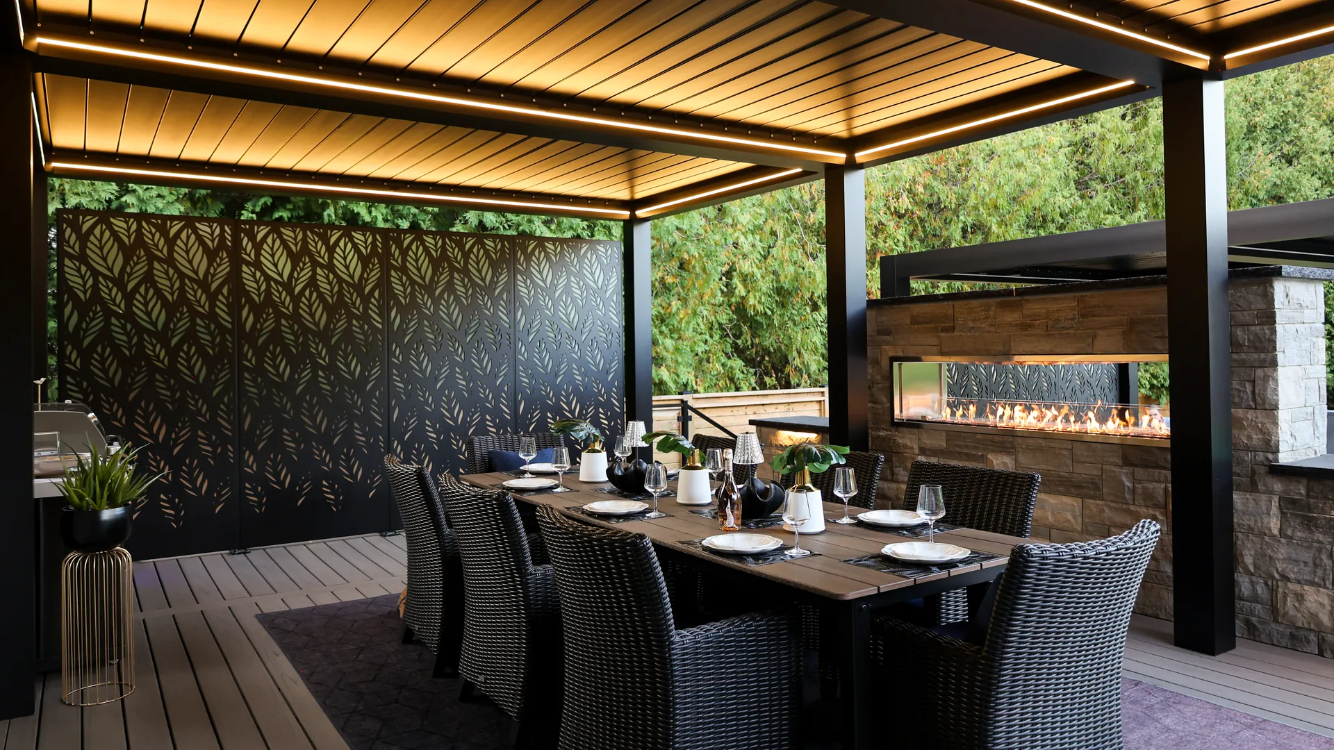 Pergola dining area with a table set for dinner, warm LED lights, laser-cut privacy panels and a linear gas fireplace