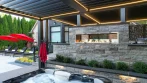 Backyard Pergola - photo 5 Black aluminum pergola with fireplace and grill seen from the hot tub, with the pool patio and red umbrellas on the left