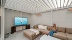Pool house with pergola roof: aluminum walls, a TV and half-open white louvers above the sofa