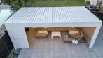 Aerial view of a white aluminum pool pergola with the louvered roof closed over a lounge area beside the pool