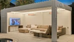 Pool pergola idea at night: white louvered pergola with LED perimeter lighting, heaters and an outdoor TV lounge