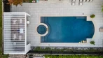 Top view of a white swimming pool pergola at the end of a backyard pool with a round spa